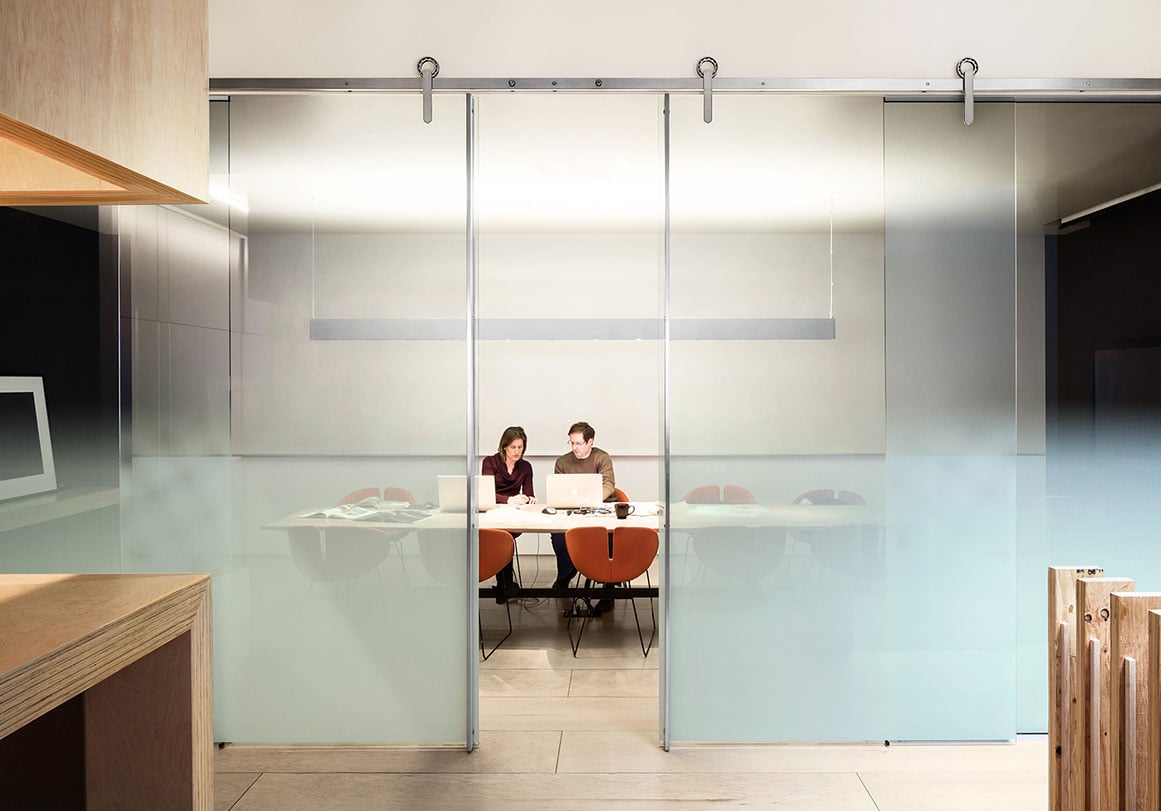Krownlab modern sliding door hardware in brushed steel finish with glass office conference room