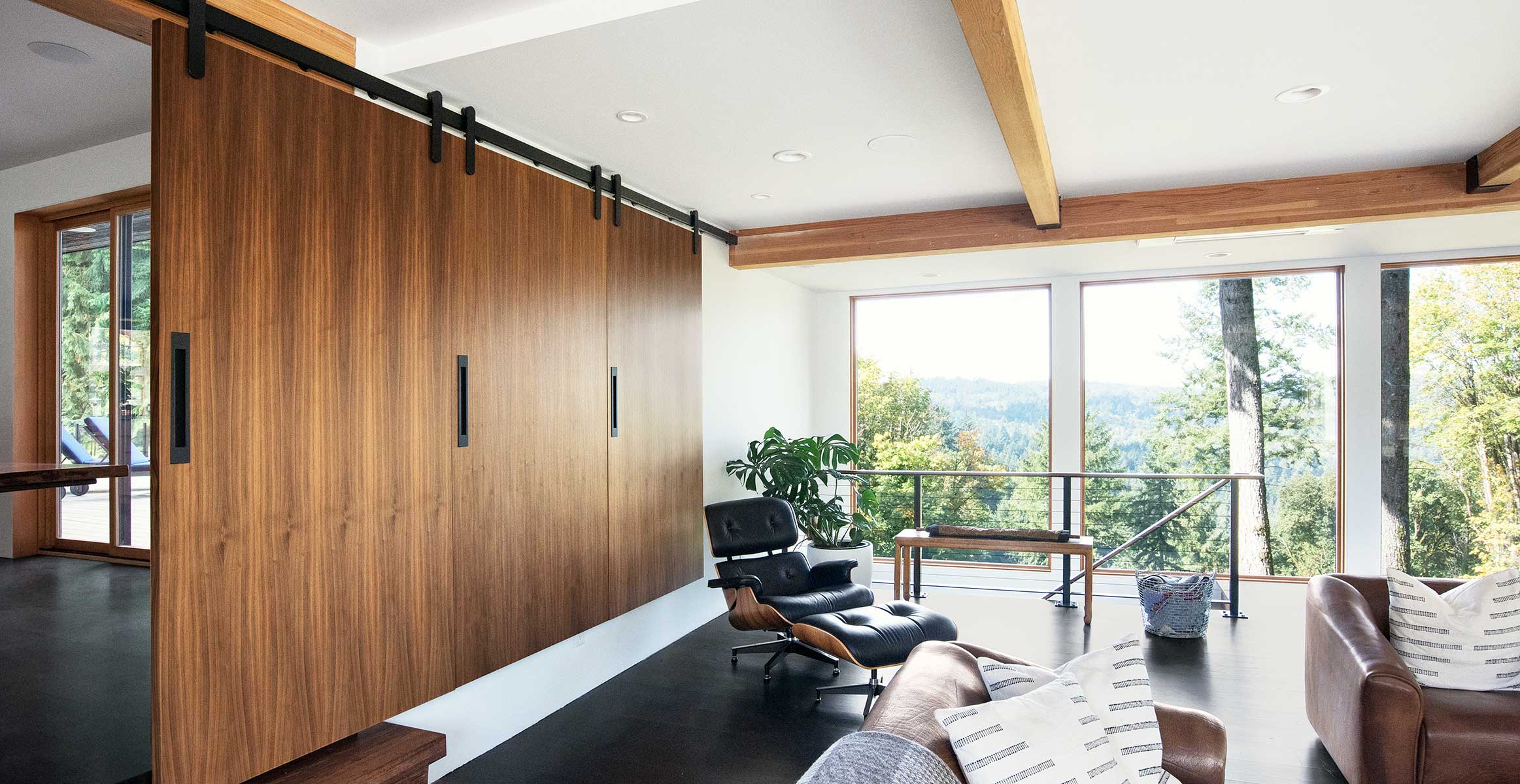 Walnut doors with recessed linear door pull by Krownlab in black stainless finish in modern living room.