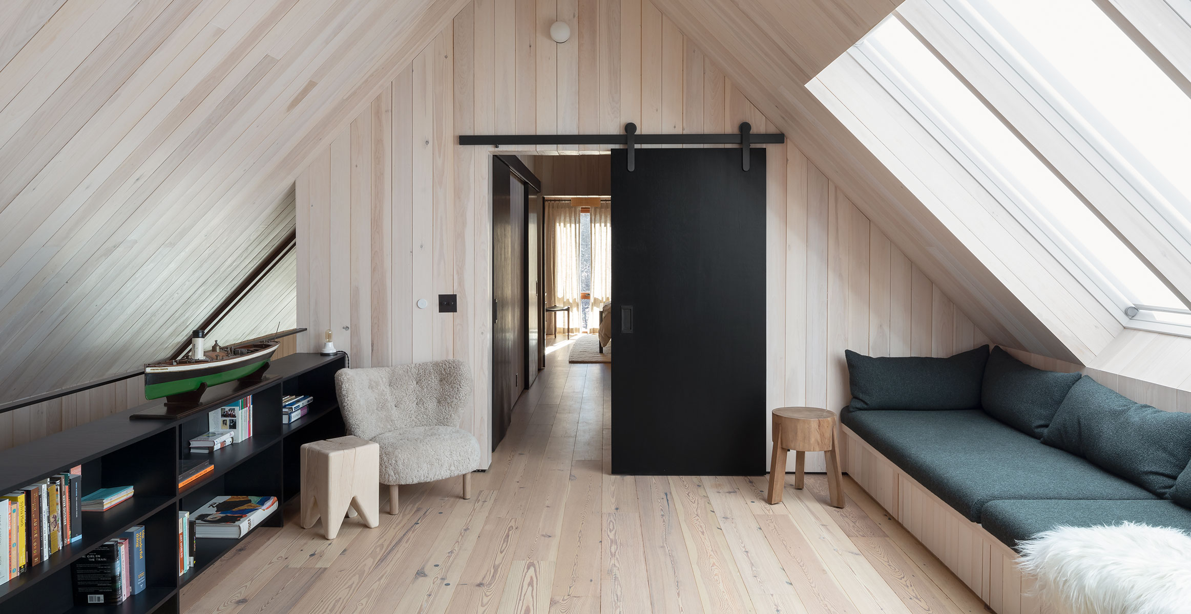 Modern sliding barn door hardware in black stainless finish from Krownlab with black door in white oak cabin interior