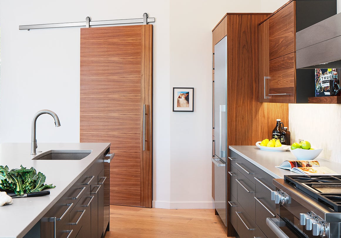 Krownlab modern sliding door hardware in brushed stainless finish in modern kitchen with walnut veneer barn door