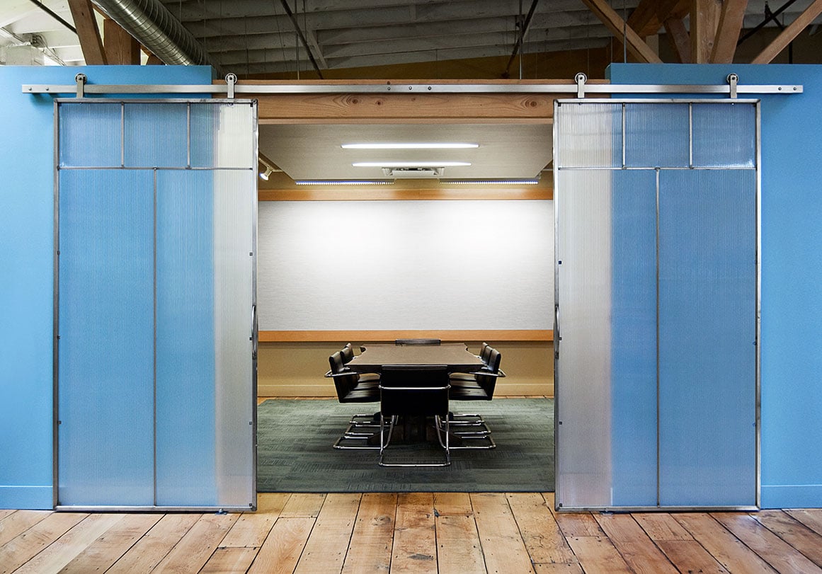 Modern office with bi-parting sliding glass barn doors with Krownlab hardware in brushed stainless