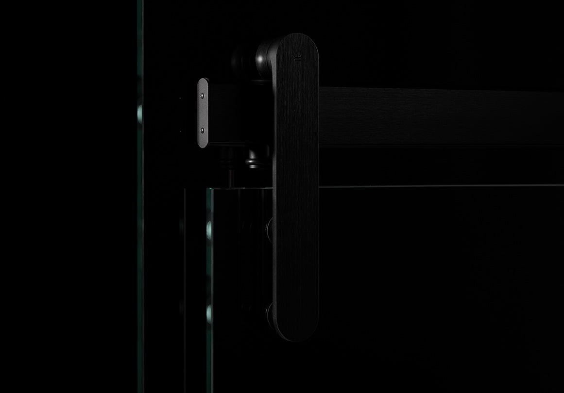 Loki sliding door hardware in Black Satin finish installed with a glass panel