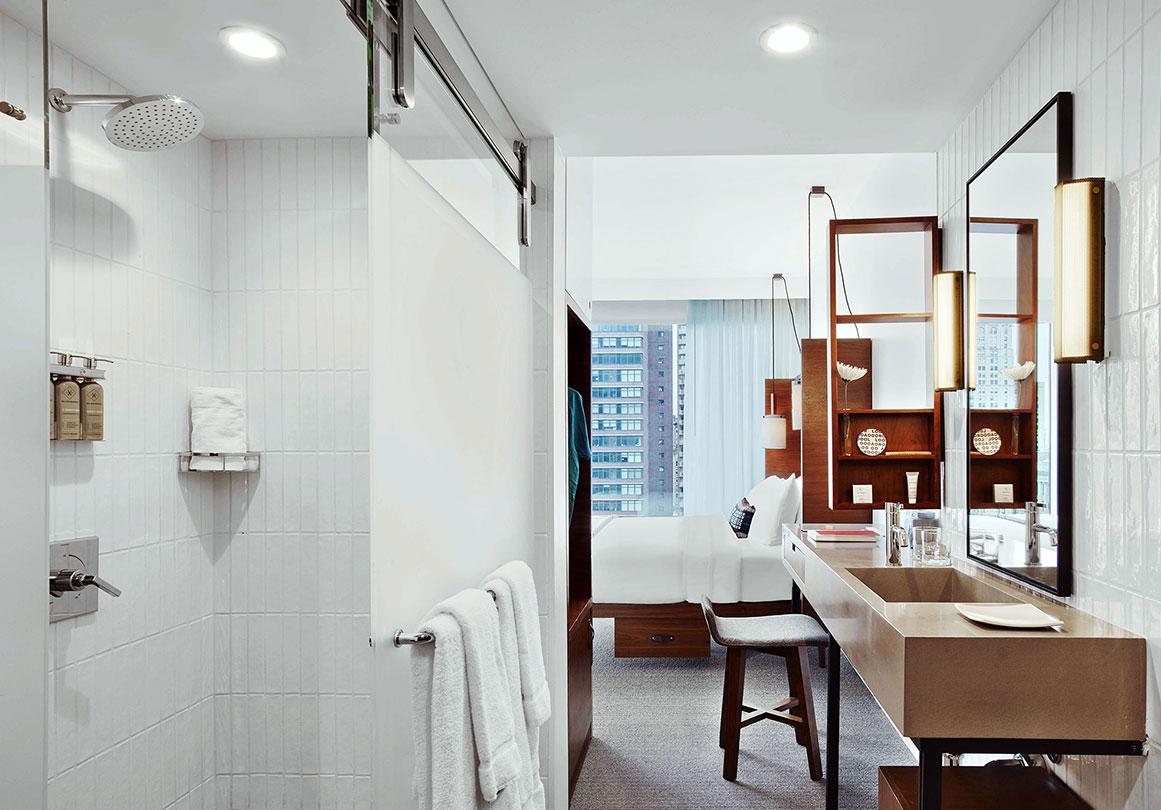 Oden sliding barn door hardware installed on glass shower stall in a modern hotel interior
